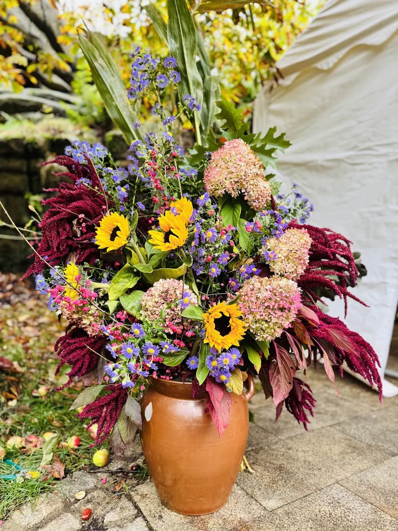 Herbststrauß mit Sonnenblumen im Steinkrug