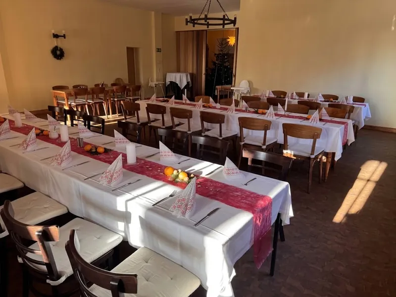 Weihnachtlich eingedeckte Tafeln im Saal der Hochsteinbaude – rote Läufer, Servietten und Weihnachtsstern am Fenster